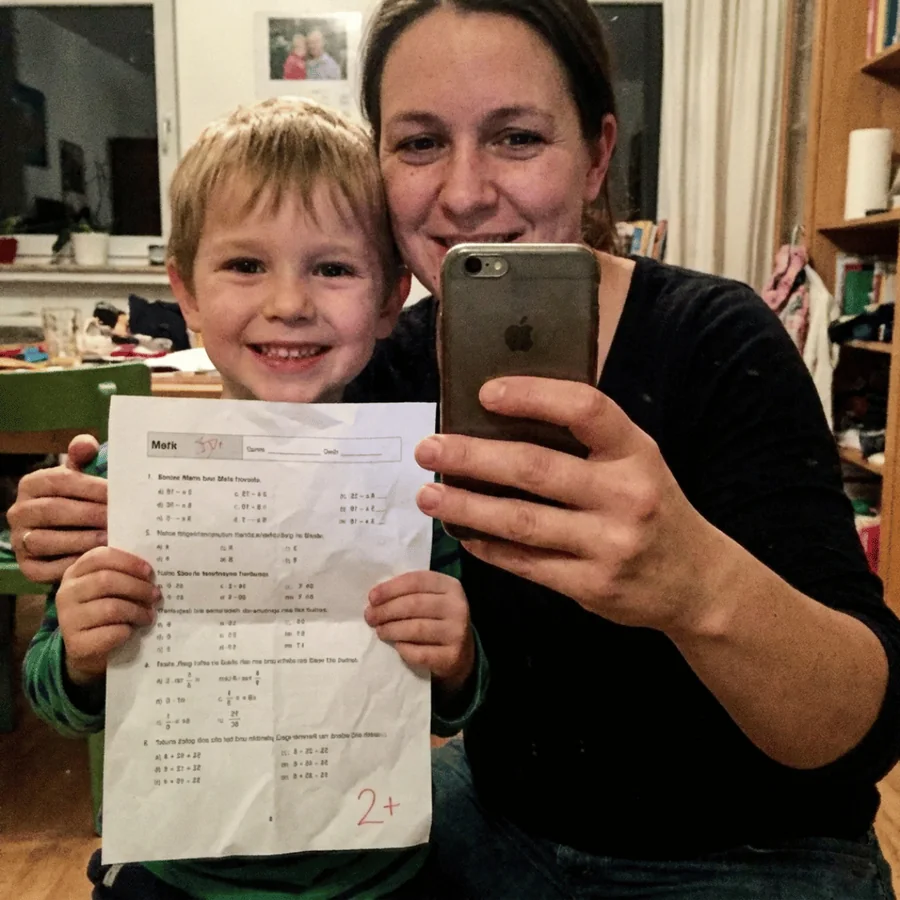 Mutter und Sohn halten eine Mathe-Arbeit mit der Note 2+ in die Kamera